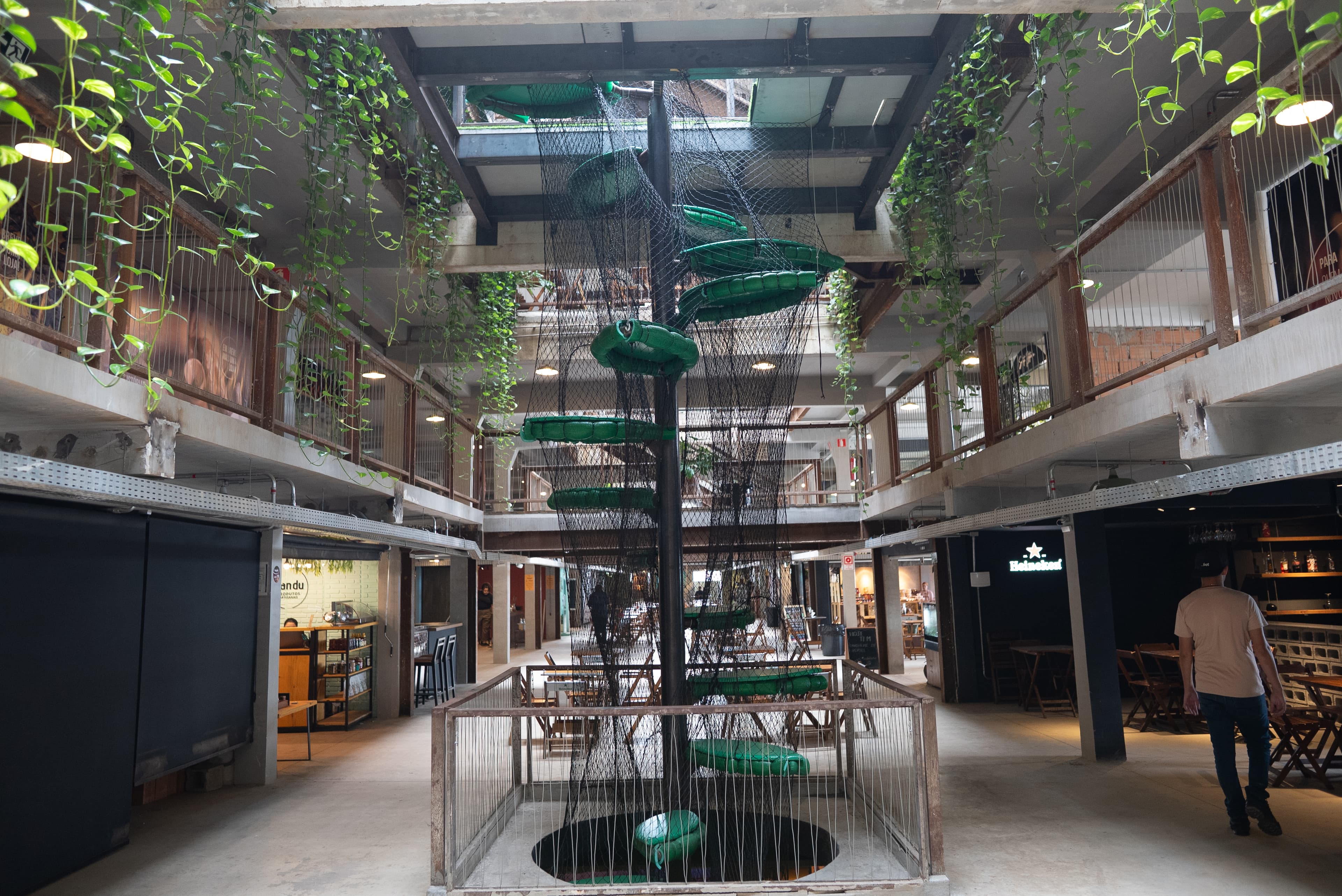 Átrio vertical da Casa do Sol Estúdios com plataformas verdes suspensas e leitura de mirante