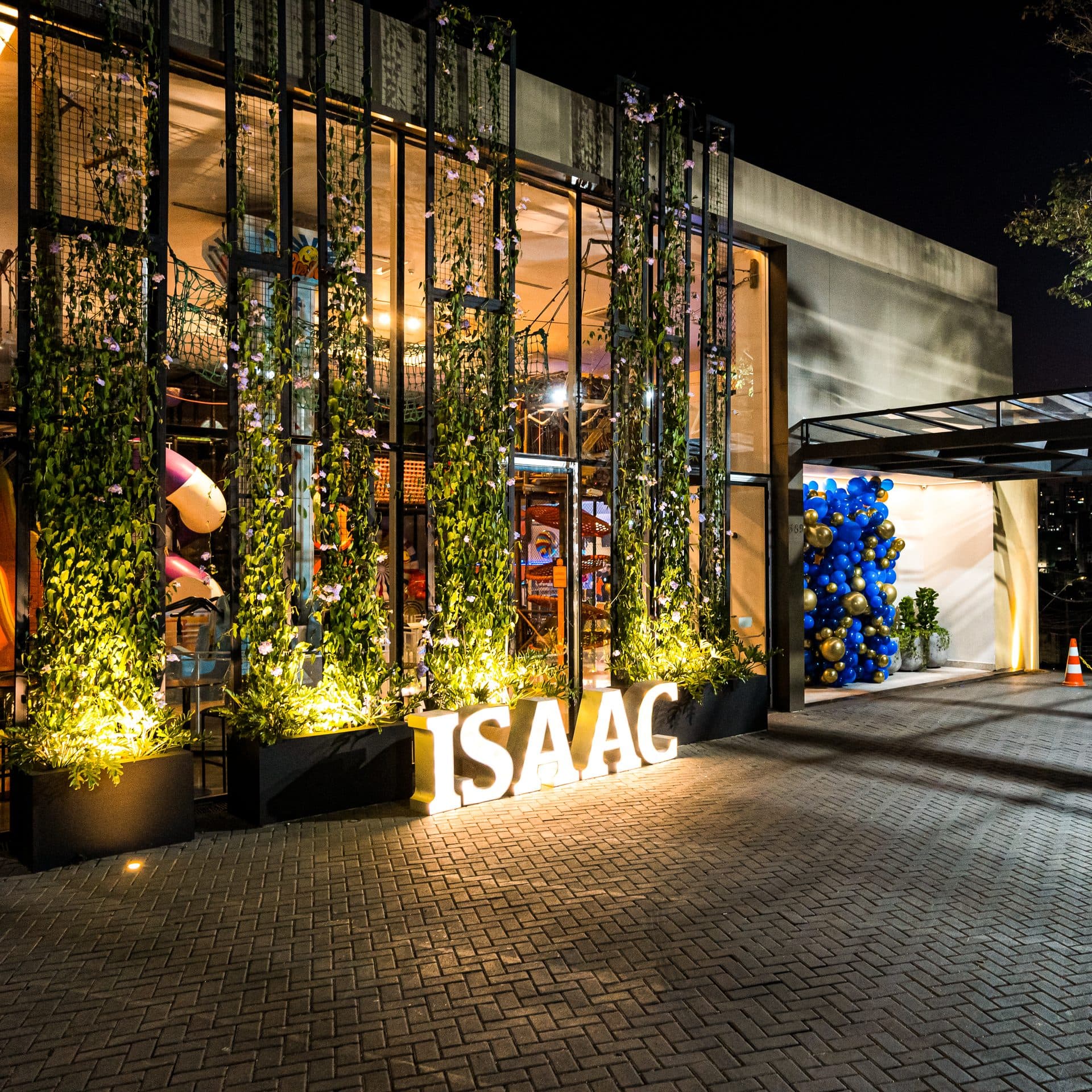 Fachada noturna da Casa do Sol Jardim com vegetação iluminada