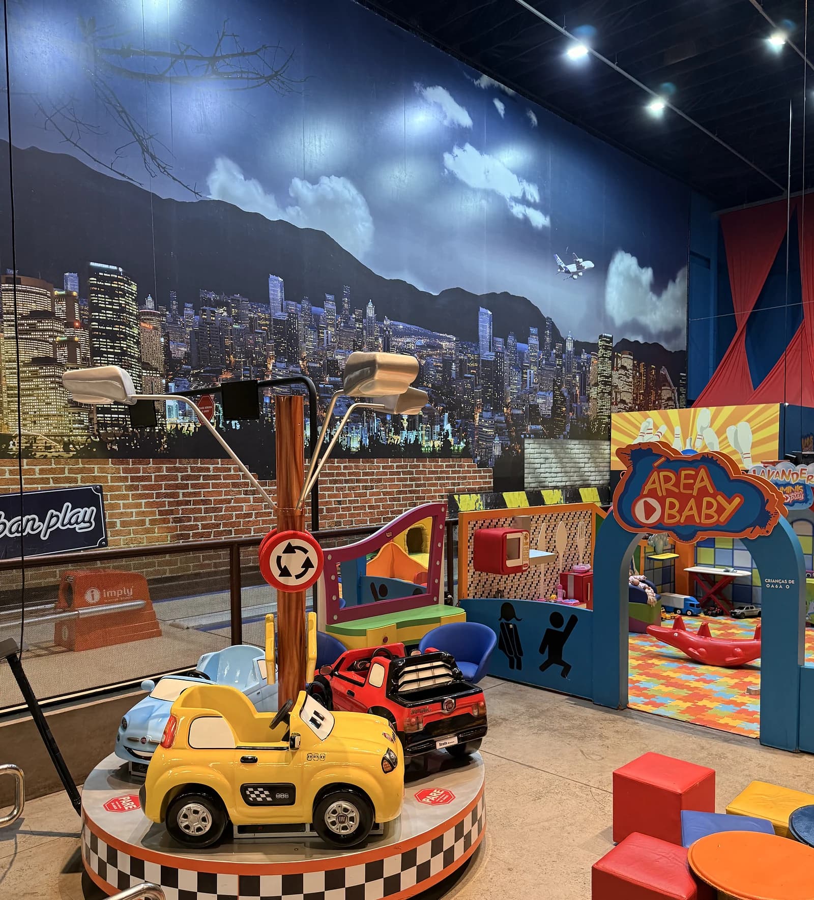 Carrossel de carrinhos e entrada da área baby, com o mural da cidade ao fundo.