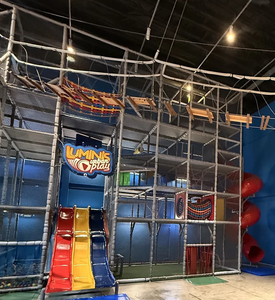 Kid play com estrutura metálica de vários níveis e escorregadores coloridos.