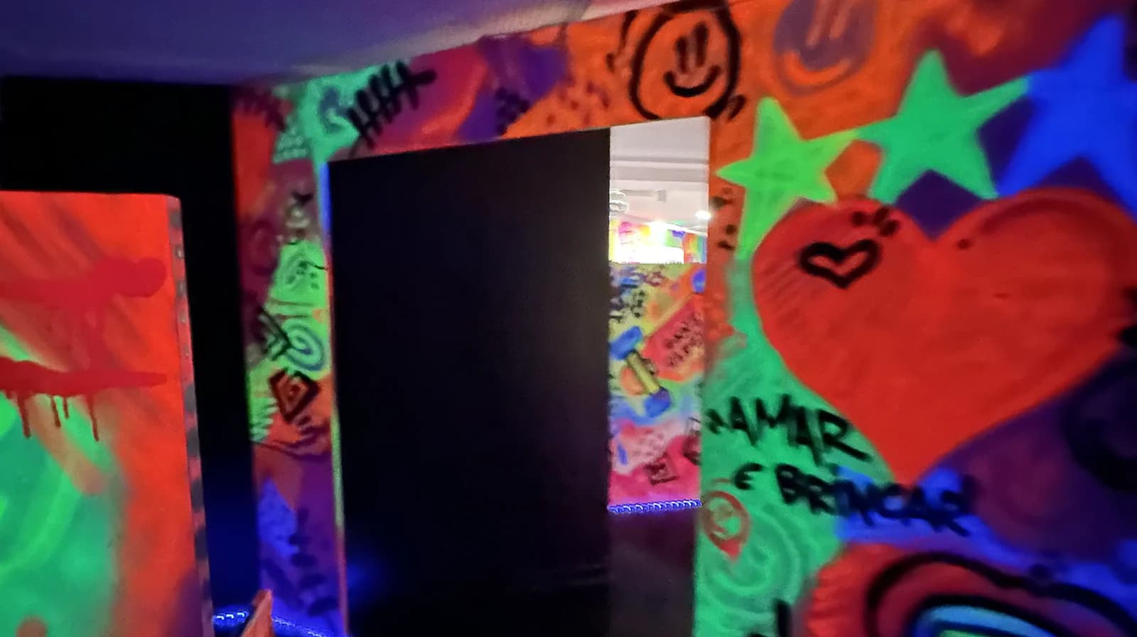 Sala neon com grafite colorido nas paredes sob luz negra.