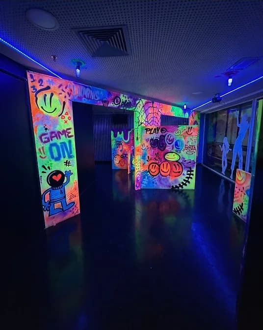 Corredor da sala neon com grafites acesos pela luz negra.