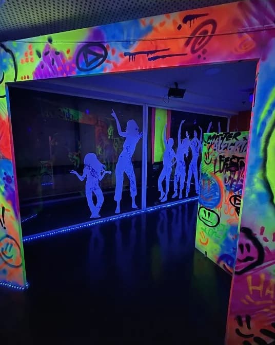 Silhuetas dançando pintadas nas paredes da sala neon.